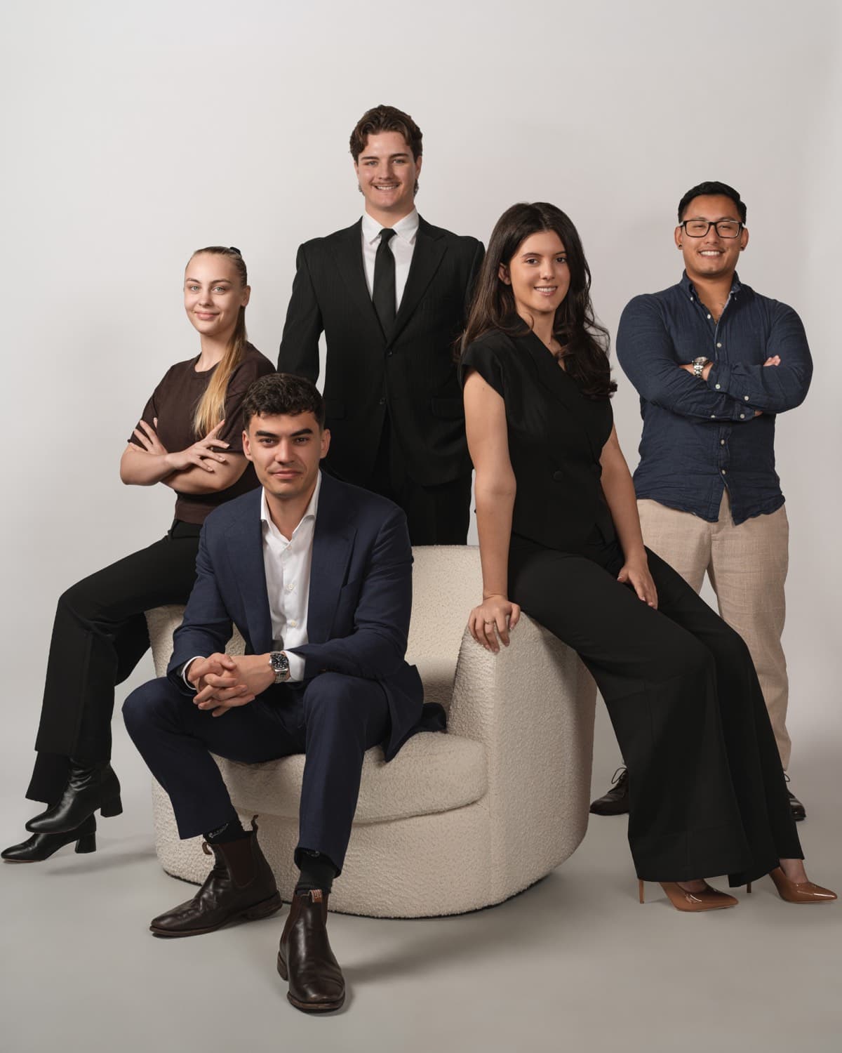 The Toohey Property Management team gathered around an armchair in the studio